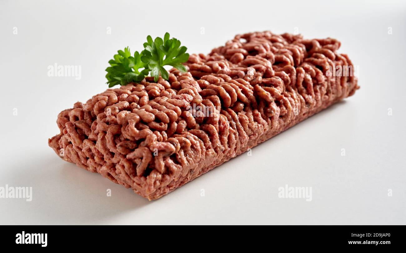 Pat di carne grezza di mince vegana a base di piante guarnita con prezzemolo in una vista diagonale su bianco con copyspace Foto Stock