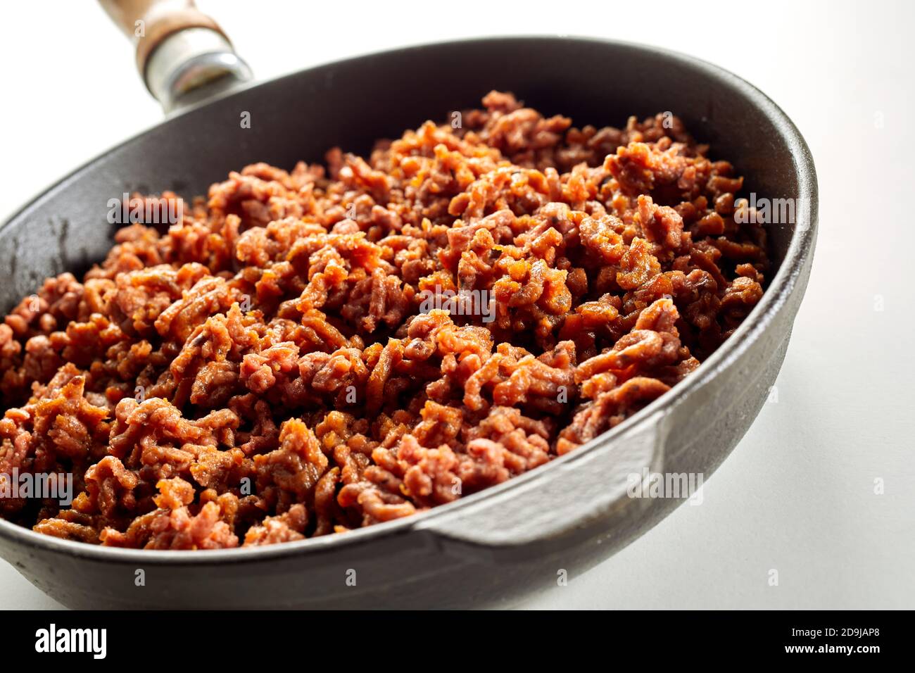 Gustoso pasto a base di soia piccante di carne mince vegana in una padella ha visto l'angolo inclinato su bianco in primo piano Foto Stock