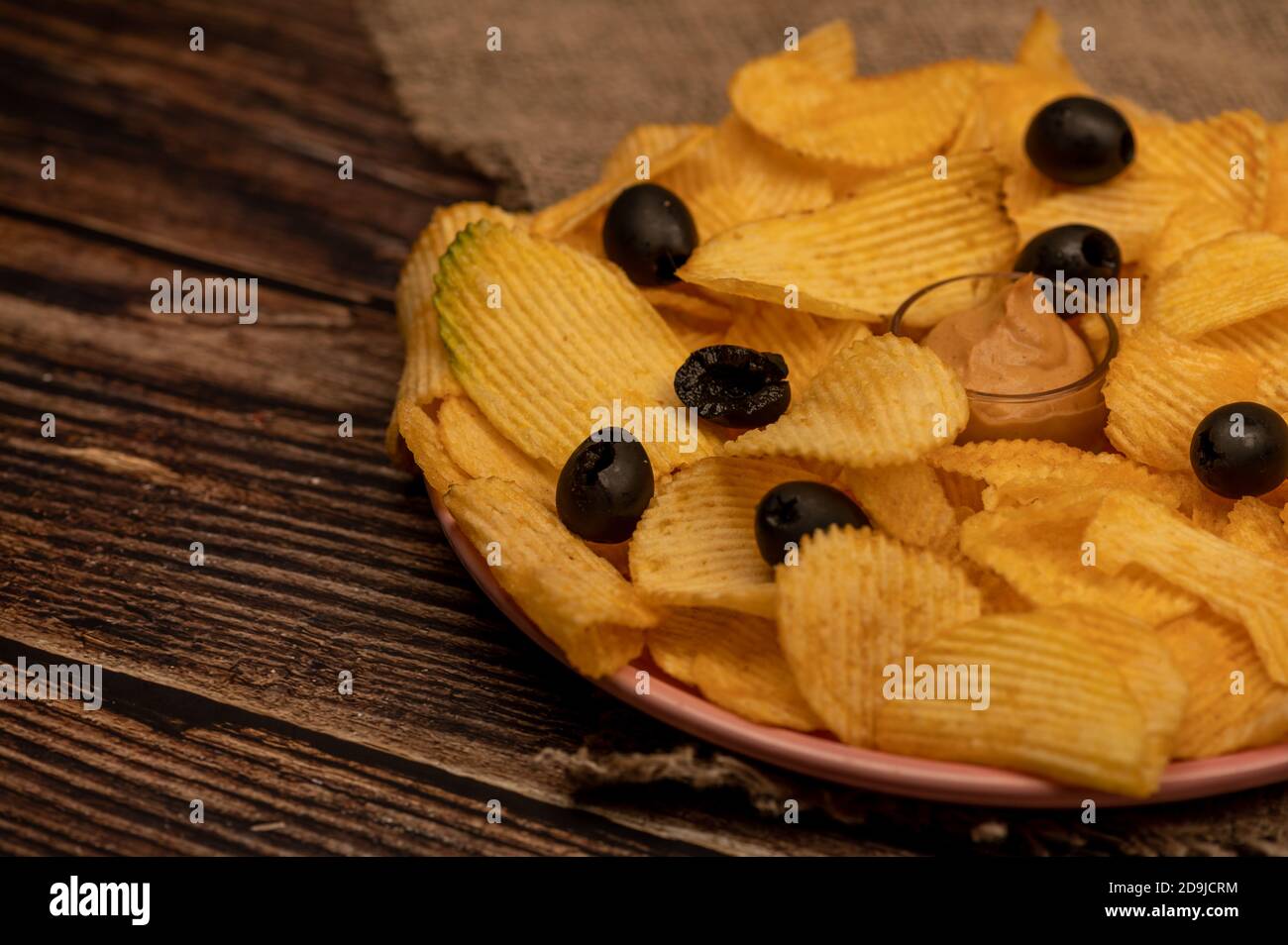 Patatine croccanti e deliziose con salsa di senape e olive su un panno di casa grossolano. Primo piano Foto Stock