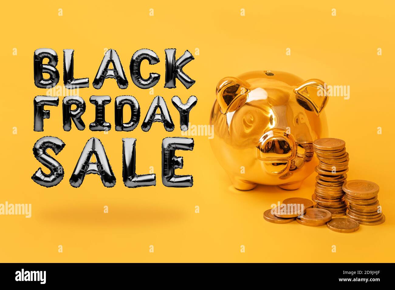 Golden piggy bank con torri di denaro su sfondo giallo con testo Black Friday sale. Pila di monete in euro vicino alla scatola di soldi d'oro. Denaro maiale, denaro Foto Stock