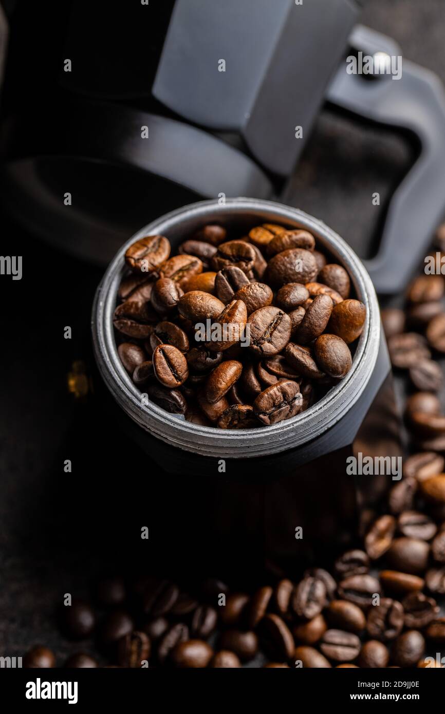 Caffè in grani e macchina per caffè bialetti. Vaso Moka su tavolo nero. Foto Stock