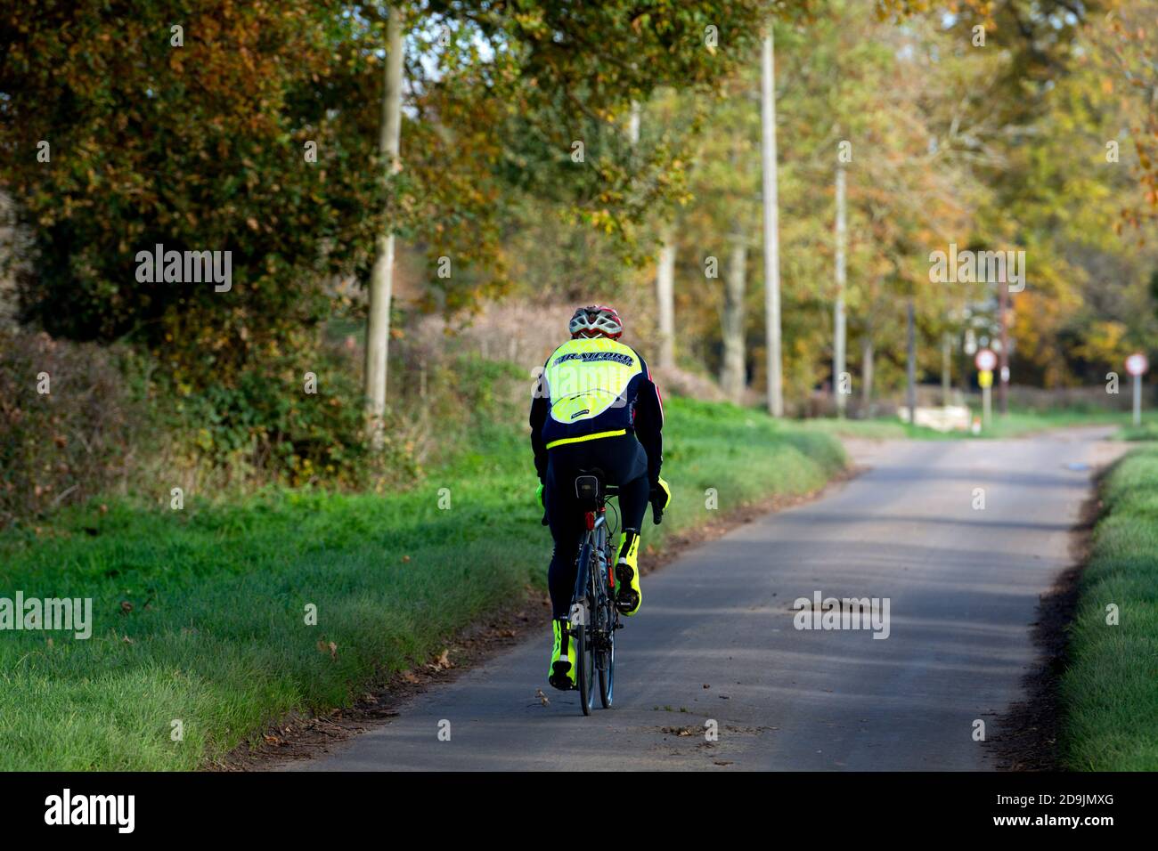 Un ciclista su una strada di campagna in autunno, Sherbourne, Warwickshire, Inghilterra, Regno Unito Foto Stock