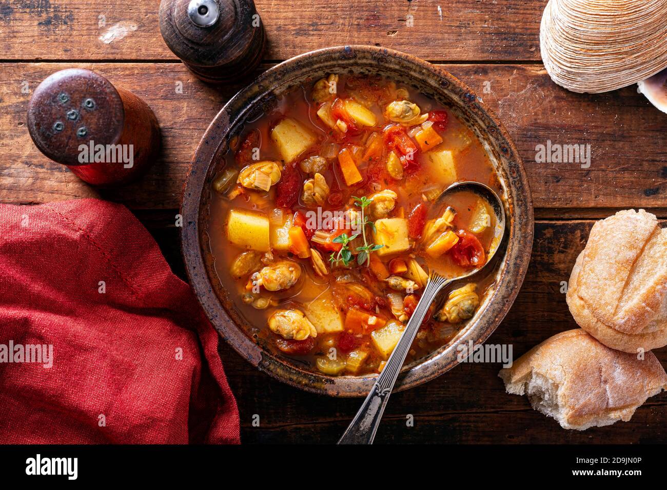 Una ciotola di deliziosa zuppa di vongole di Manhattan con guarnitura di timo fresco su un rustico tavolo di legno. Foto Stock