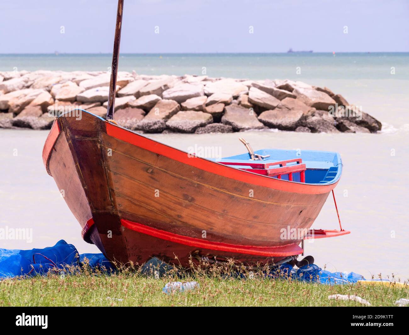 Pescatore che lavora sulla sua tradizionale barca di legno dopo una giornata in mare in una giornata piovosa nella provincia di Rayong in Thailandia. Foto Stock