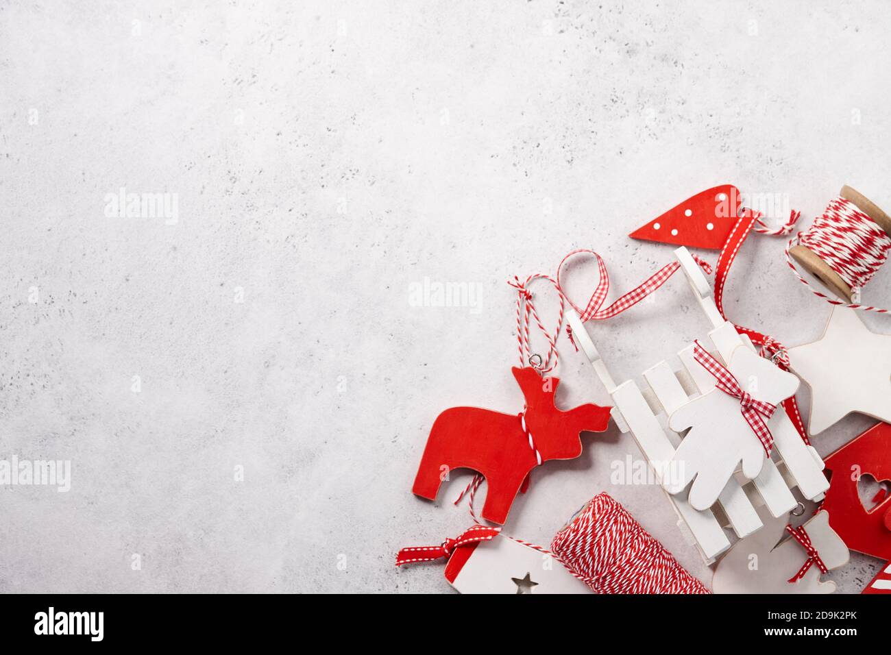 Giocattoli di Natale in legno vintage rosso e bianco su sfondo bianco testurizzato, spazio copia. Decorazione per le vacanze. Foto Stock