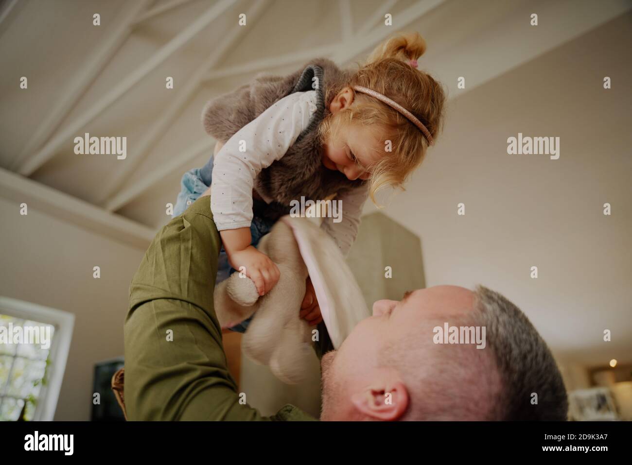 Giovane padre che solleva il bambino in aria mentre gioca a casa Foto Stock