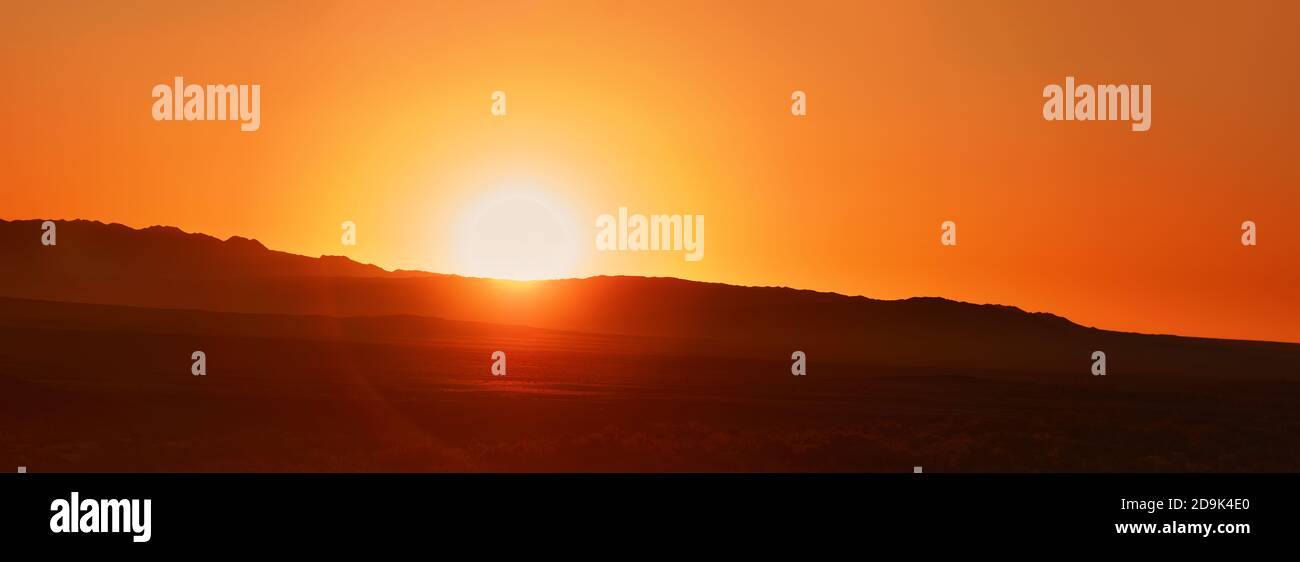 Bella Alba sulle montagne contorno delle montagne, alba arancione. Disco del sole e i primi raggi del sole Foto Stock