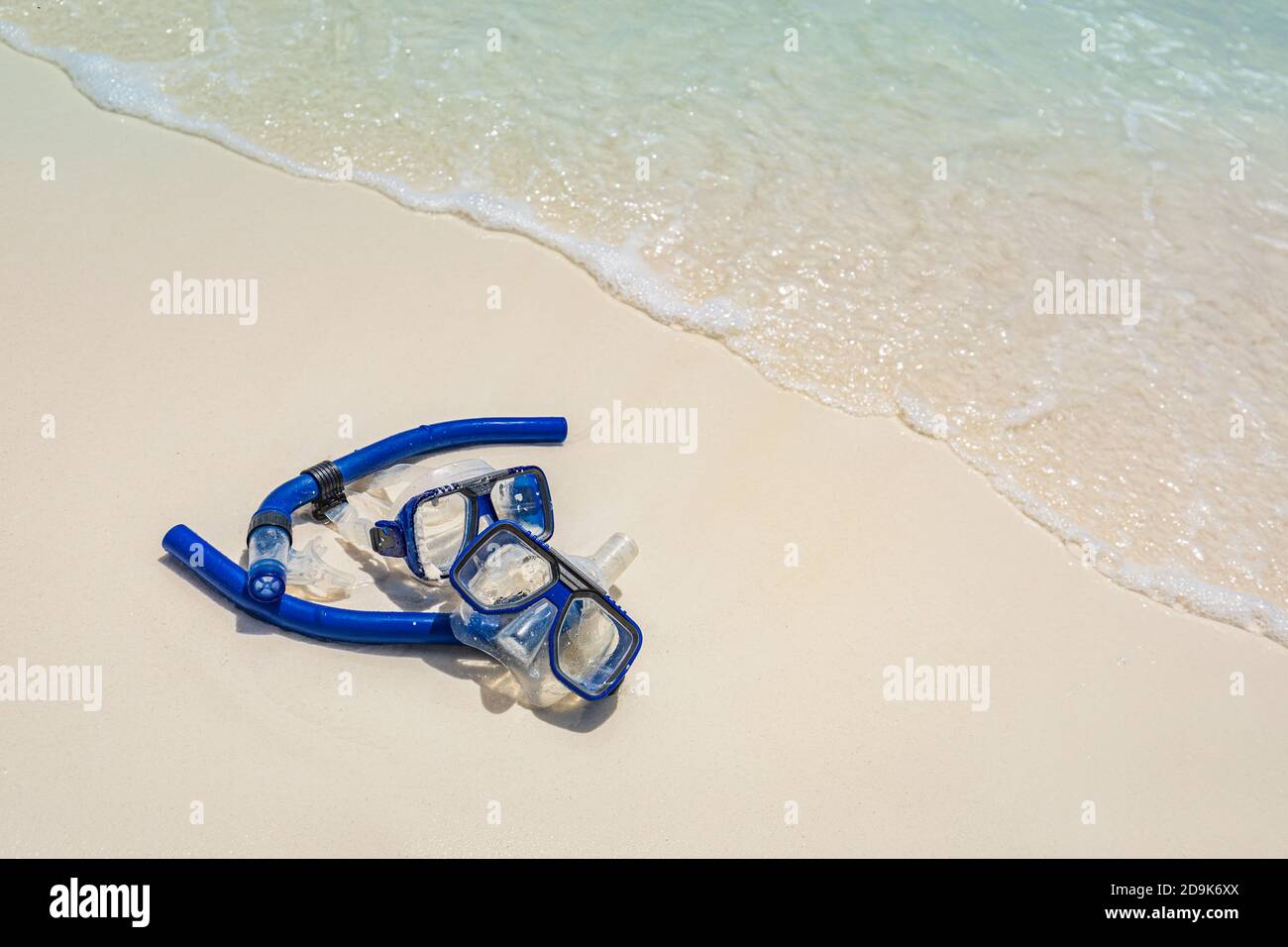 Due maschere e attrezzatura da snorkeling nelle onde di surf della spiaggia di sabbia. Attività sportive esotiche all'aperto, hobby ricreativo. Spiaggia sabbia e vista mare paesaggio Foto Stock