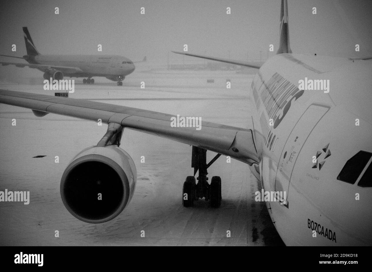 Vista in bianco e nero di un aereo in attesa di passeggeri a Βoard. JFK in un giorno di neve. New York City, Stati Uniti Foto Stock
