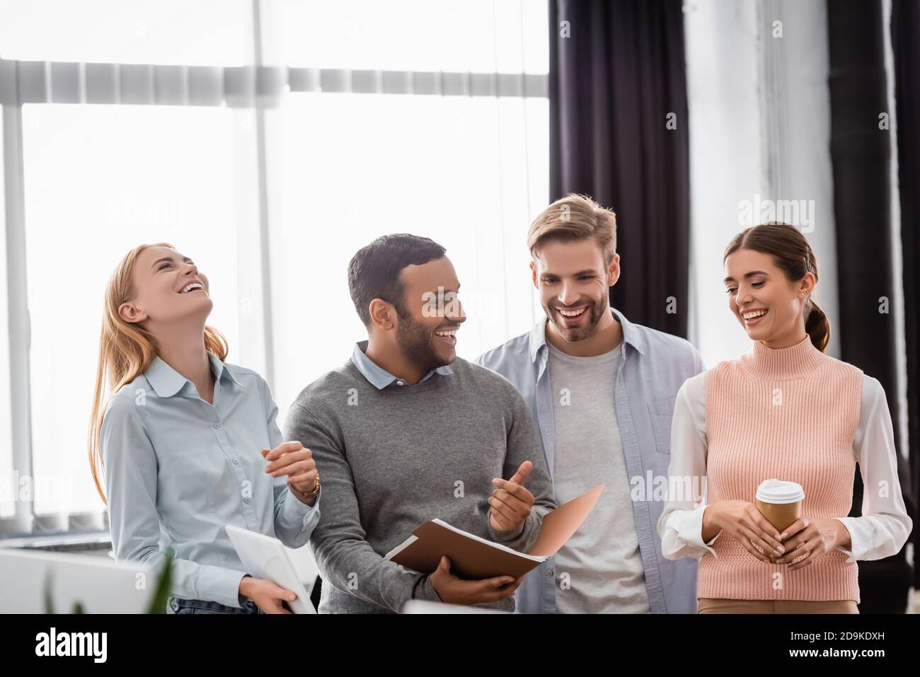 Uomini d'affari multietnici positivi con caffè da andare e piegatrice di carta lavorare in ufficio Foto Stock