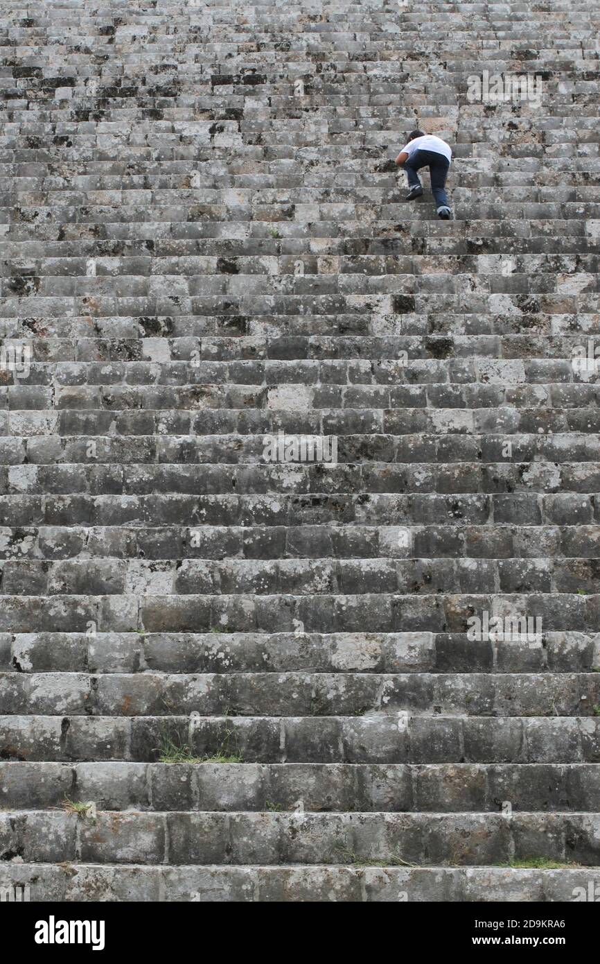Un ragazzo che sale sui ripidi gradini di una piramide alle rovine di Uxmal a Yucatan, Messico. Foto Stock