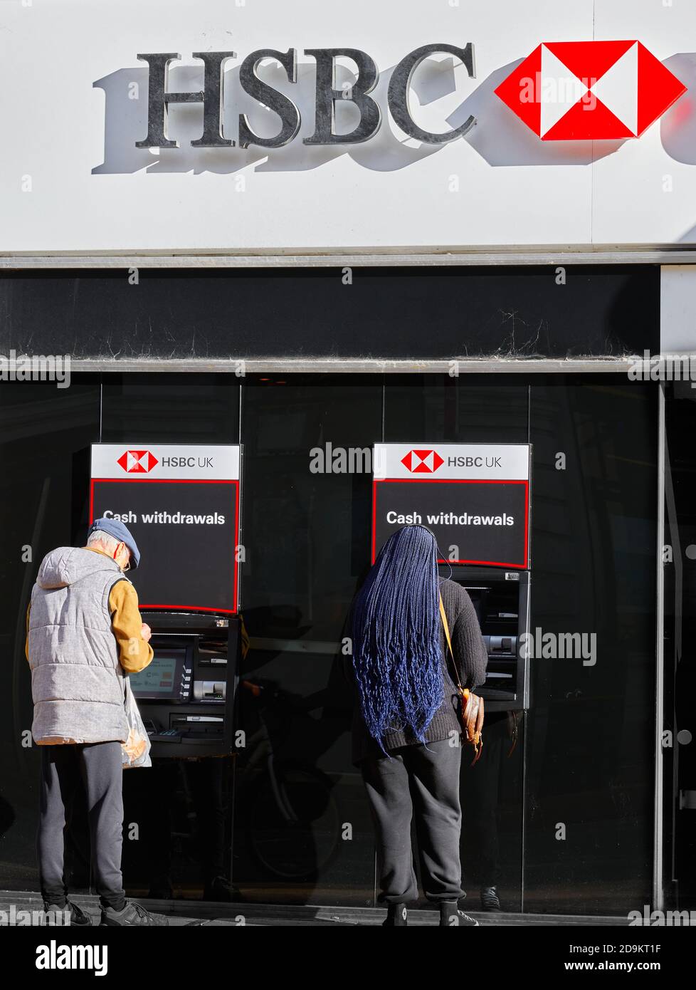 Un uomo e una donna prelevano denaro dalle macchine per il prelievo di contanti presso la banca HSBC, Cambridge, Inghilterra. Foto Stock