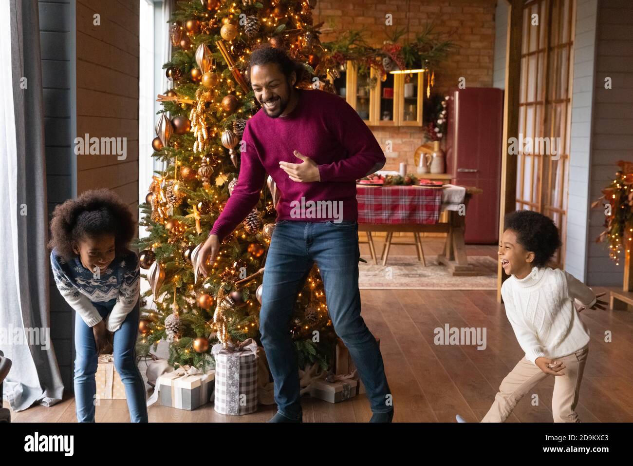 Il padre afroamericano si è divertito molto con i bambini che si divertono a Natale Foto Stock