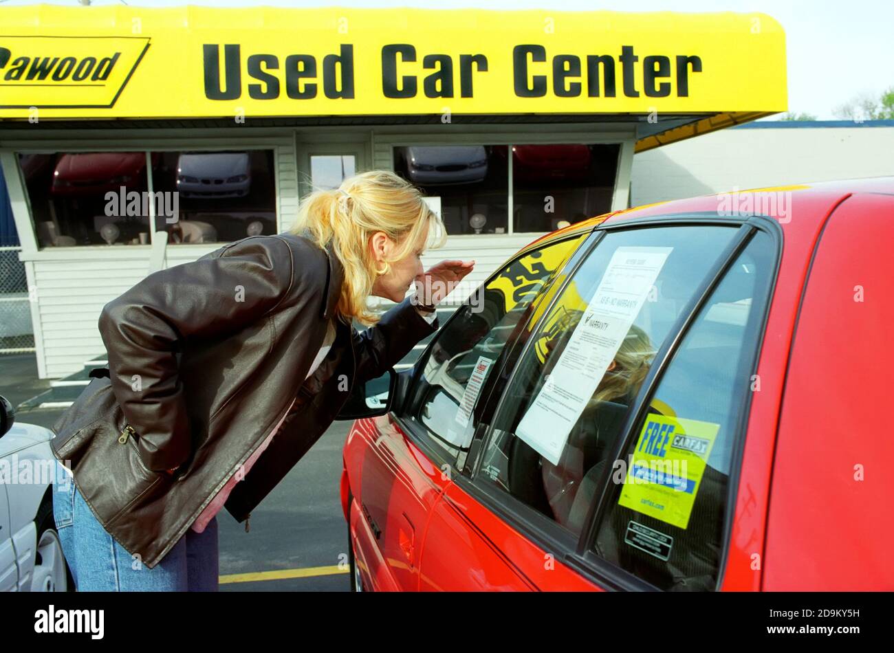 Collegio femminile di età negozi per un automobile usata e guarda la vignetta prezzo della vettura su una automobile usata molto Foto Stock