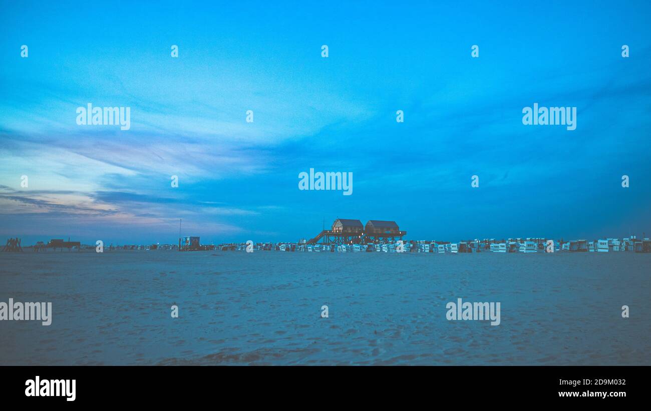 Tramonto colorato sul Mare del Nord - nella retroilluminazione del sole una tipica casa a palafitte, palafitte, palafitte, palafitte che sfidano le maree. Foto Stock