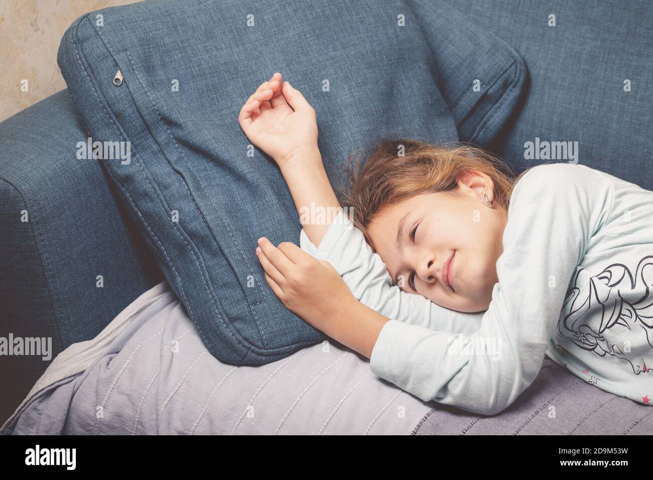 Quando è difficile svegliarsi al mattino. La ragazza non può svegliarsi. Si trova sul divano blu nei pigiami. Foto stile di vita Foto Stock