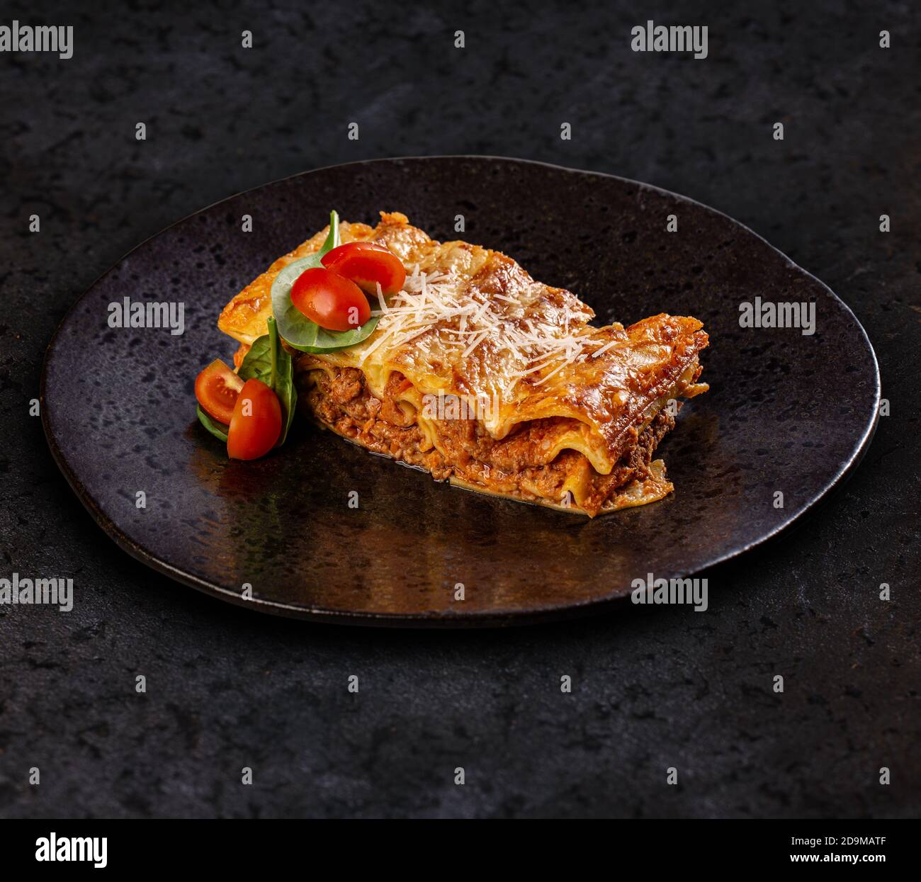 Gustosa lasagna con carne ricoperta di formaggio servita in nero piastra Foto Stock