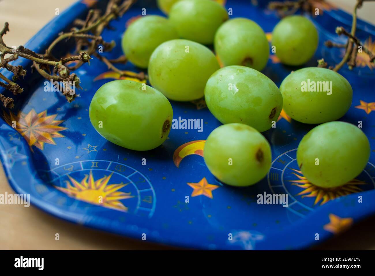 Alcune uve verdi fresche su un vassoio blu su a. tabella Foto Stock