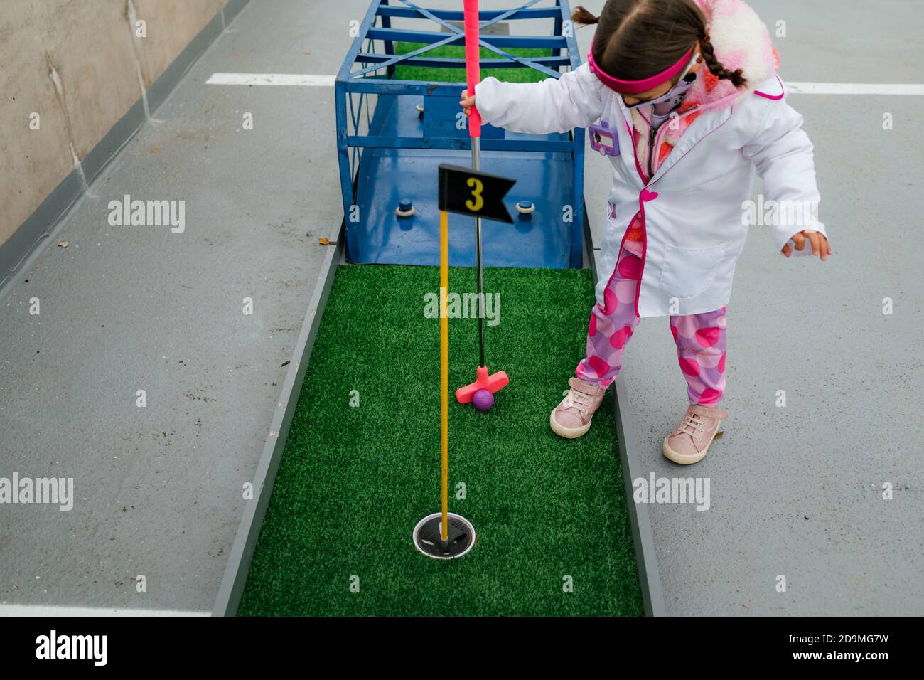 ragazza prescolare in costume medico giocando mini golf su halloween Foto Stock