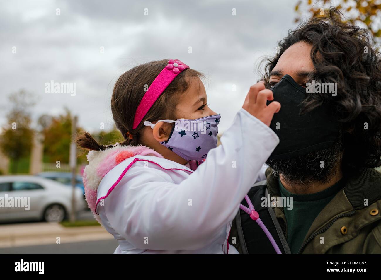 Bambina in costume halloween con papà che indossa la faccia protettiva maschera Foto Stock