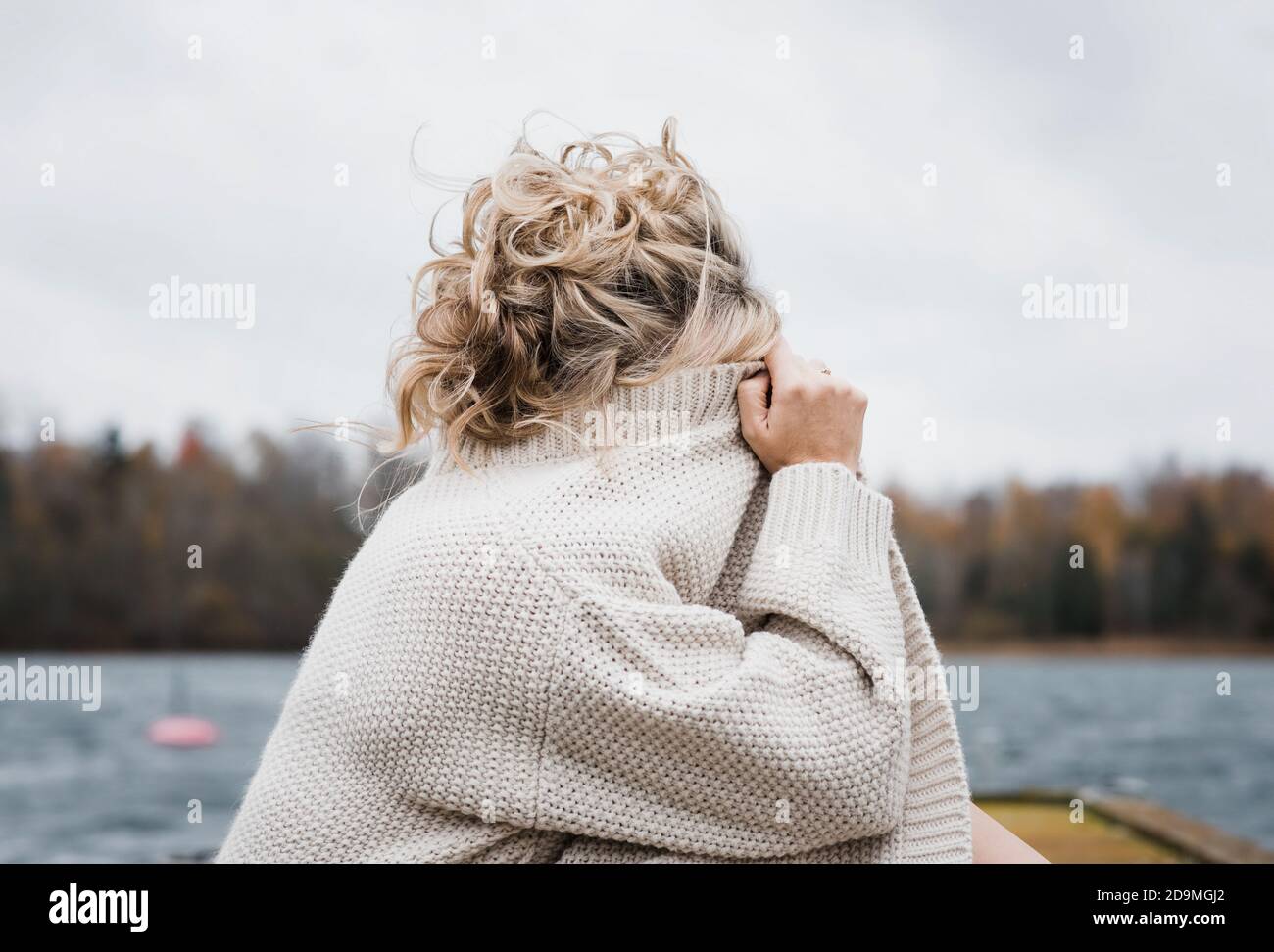 la donna si sedette fuori coprendo il viso con il cardigan Foto Stock