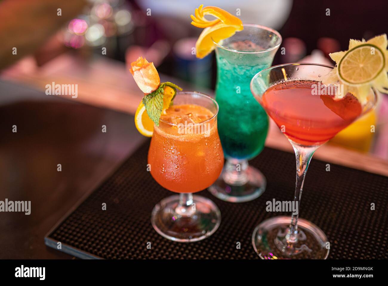 Cocktail colorati al bancone del bar. Cocktail tropicali sul tavolo del ristorante, pronti a servire. Festa della vita notturna, sottofondo di drink al bar, bottiglie sfocate Foto Stock