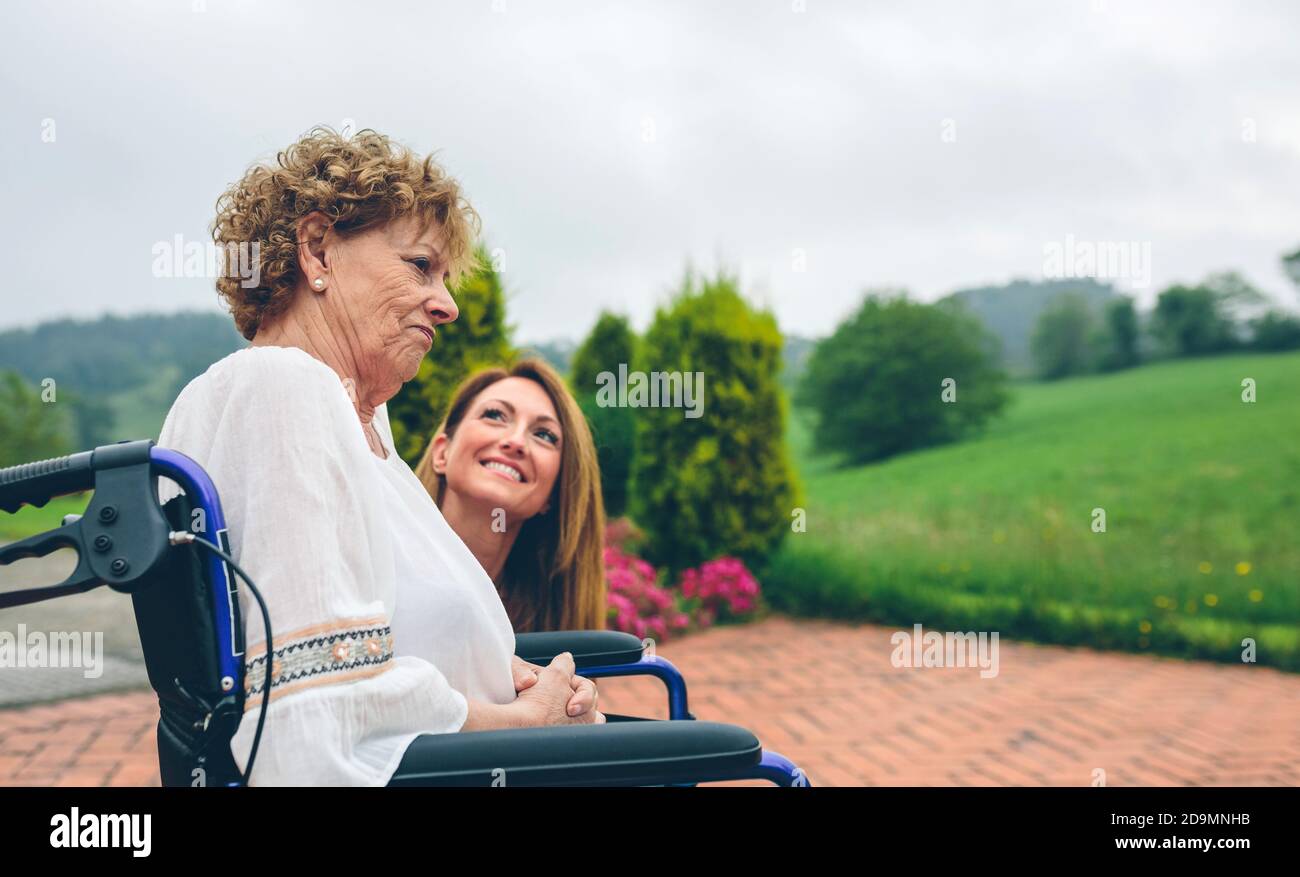 Senior insoddisfatto donna in una sedia a rotelle con sua figlia Foto Stock