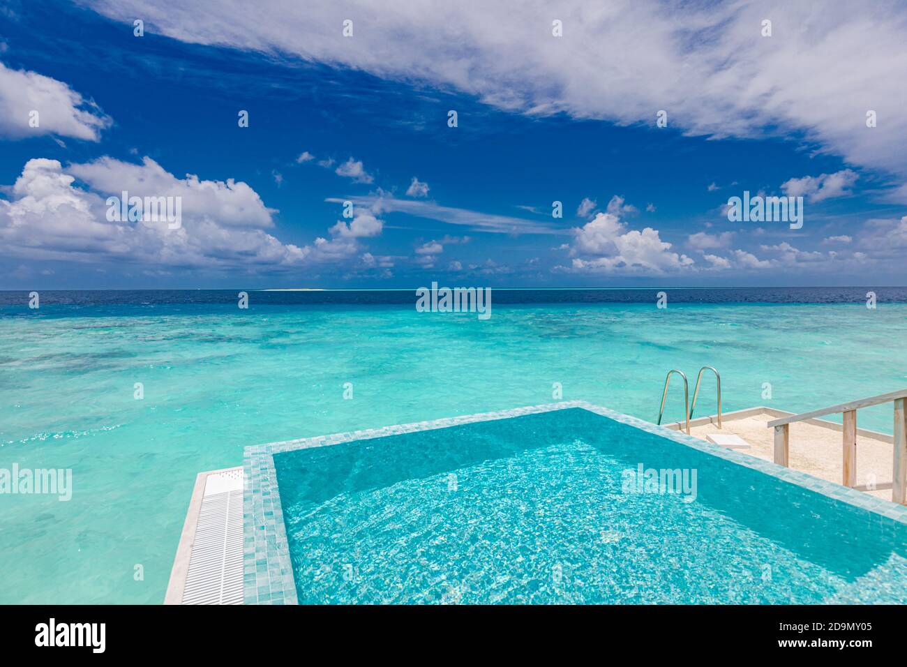 Piscina Infinity con vista mare e oceano su sfondo blu cielo. Lussuosa piscina a sfioro su una splendida laguna turchese e scala in acqua Foto Stock