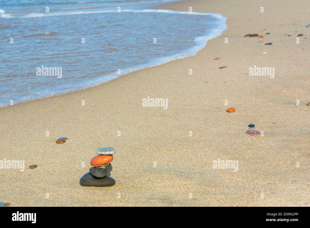 Piramide di pietre in riva al mare. Spiaggia di sabbia acqua di mare. Concetto di armonia e meditazione. Spazio di copia, messa a fuoco selettiva. Foto Stock