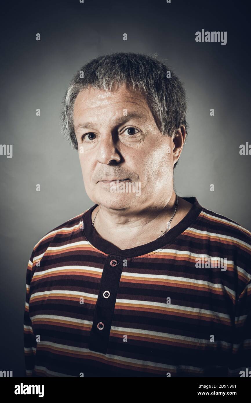 Ritratto di un uomo in studio di mezza età su sfondo grigio Foto Stock