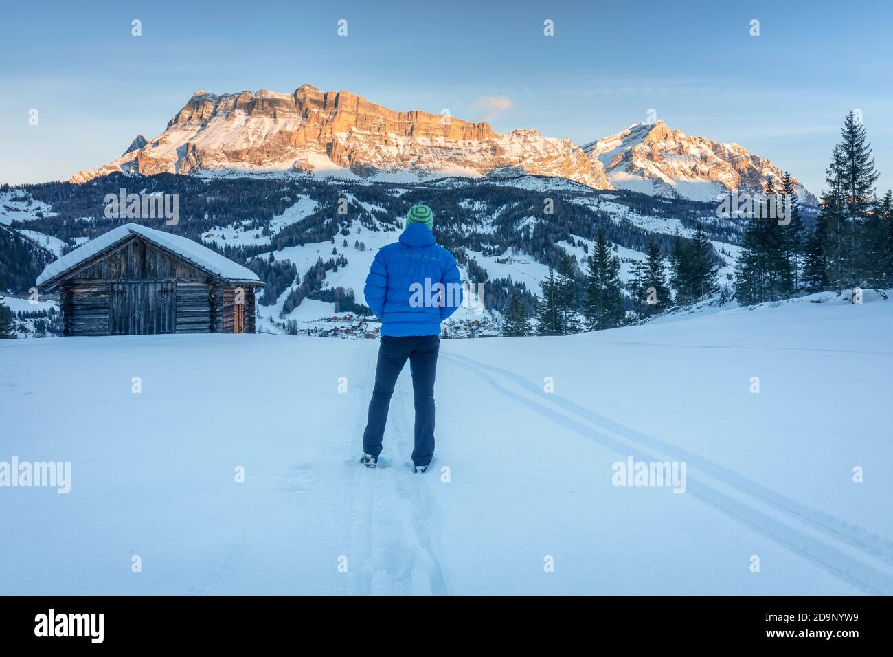 Solitario uomo (45 anni) tradizionale capanne in legno, paesaggio invernale con il Monte Cavallo / l'Ciaval / Heiligkreuzkofel sullo sfondo, Dolomiti, Abtei, Badia, valle ladina, Gadertal, Bolzano, Alto Adige, Italia, Europa Foto Stock