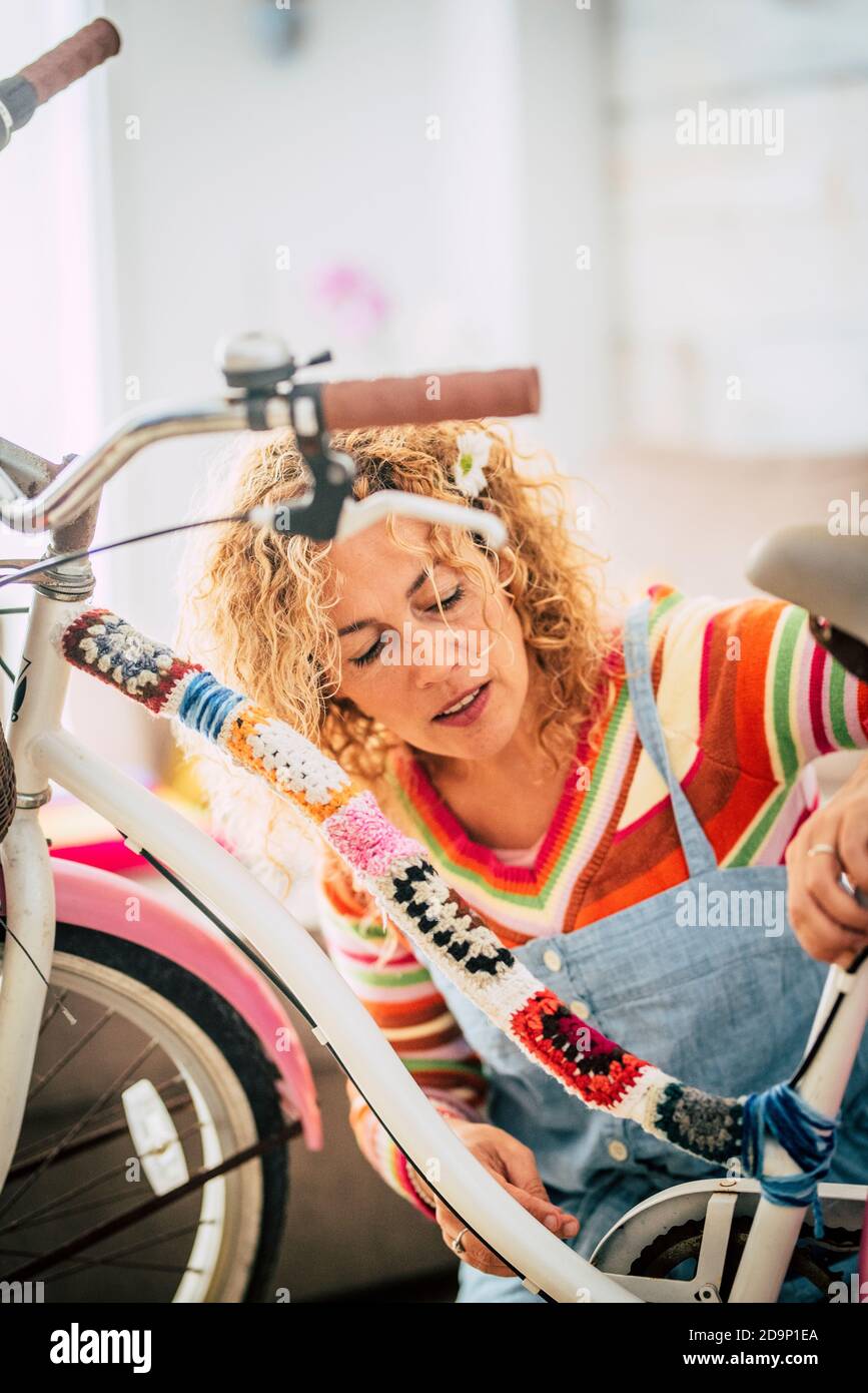 Donna adulta felice a casa in attività di svago di lavoro hobby modifica interna una moto femminile con pezzi di coperture e. pieno di colori - concetto di creatività e bicicletta hippy boho creazione - persone che godono di lavoro artistico a casa Foto Stock
