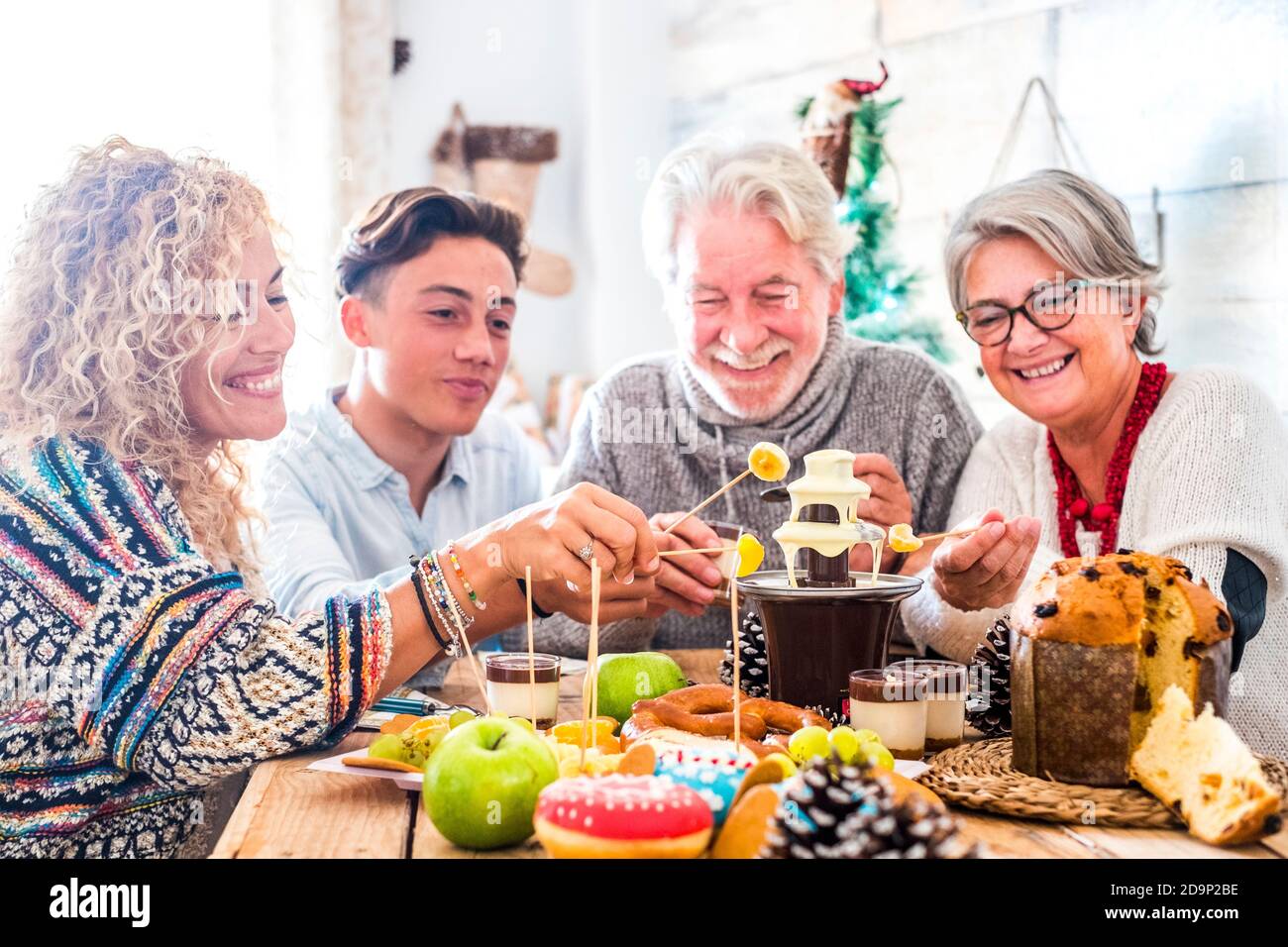 La famiglia con tre generazioni si diverti insieme a casa tua - decorazioni natalizie e felici allegri caucasici con diverse persone età e cibo di natale e decorazioni sulla tavola Foto Stock