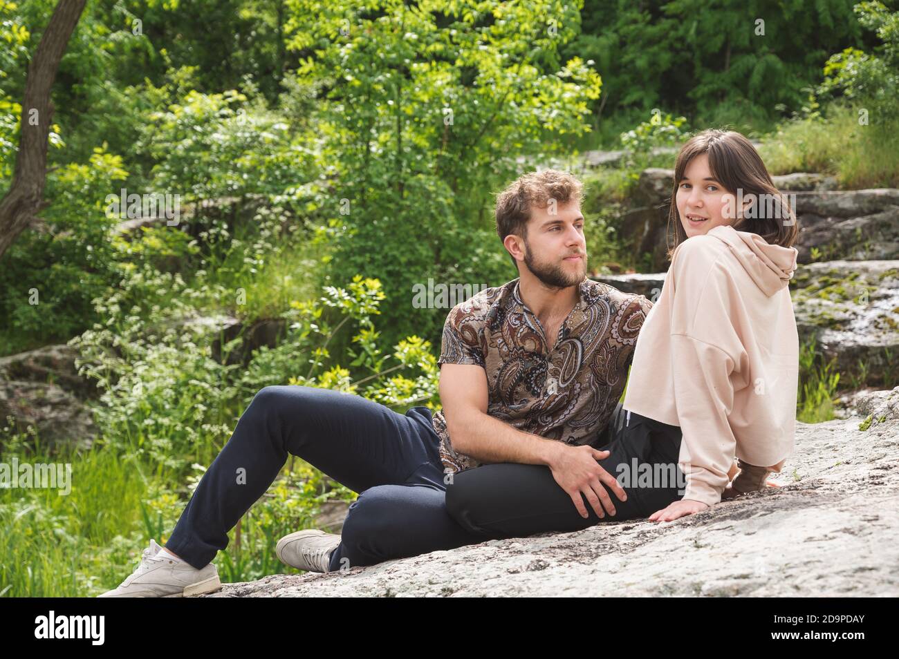 Data di bella giovane coppia seduta sulla roccia. Relazioni sensibili di belle persone. Viaggio al canyon carsico vicino al torrente. I capelli noccioli Foto Stock