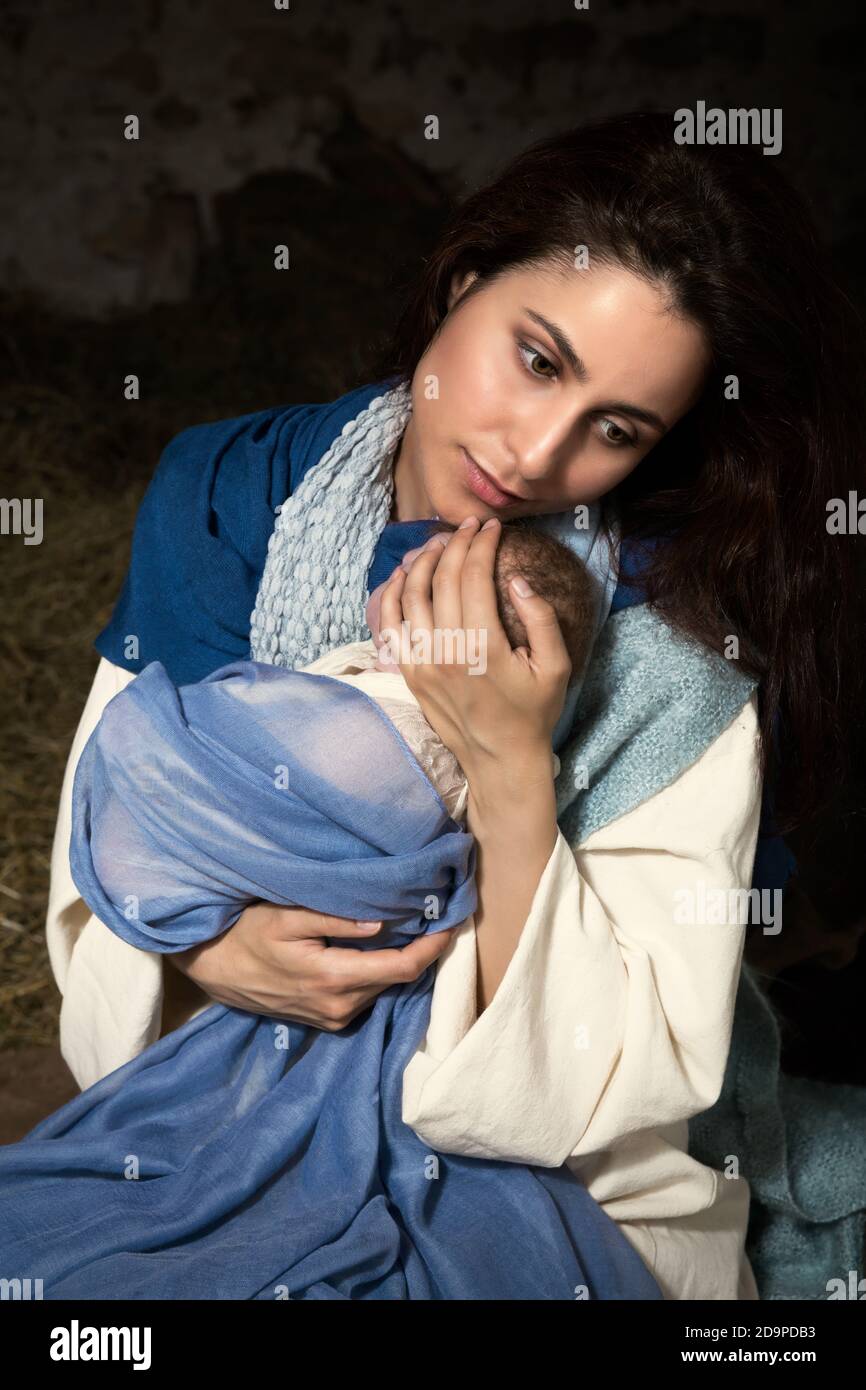 Presepe di Natale dal vivo in un vecchio fienile - gioco di reenactment con costumi autentici. Il bambino è una bambola. Foto Stock