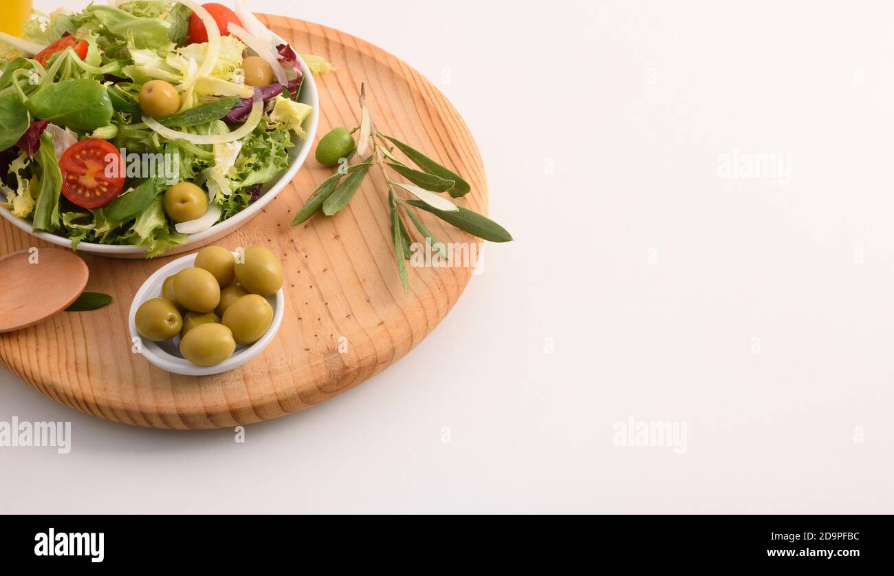 Sfondo di insalata mediterranea con prodotti freschi e olio d'oliva su una panca da cucina bianca. Vista rialzata. Composizione orizzontale. Foto Stock
