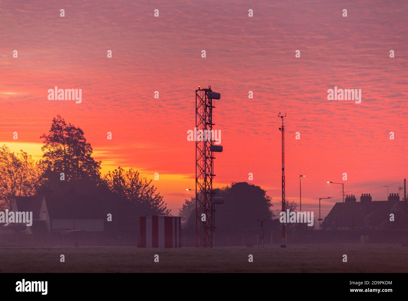 Sistema di atterraggio della torre della pendenza ILS Glide all'aeroporto di Londra Southend all'alba con cielo rosso, case sul perimetro dell'aeroporto Foto Stock