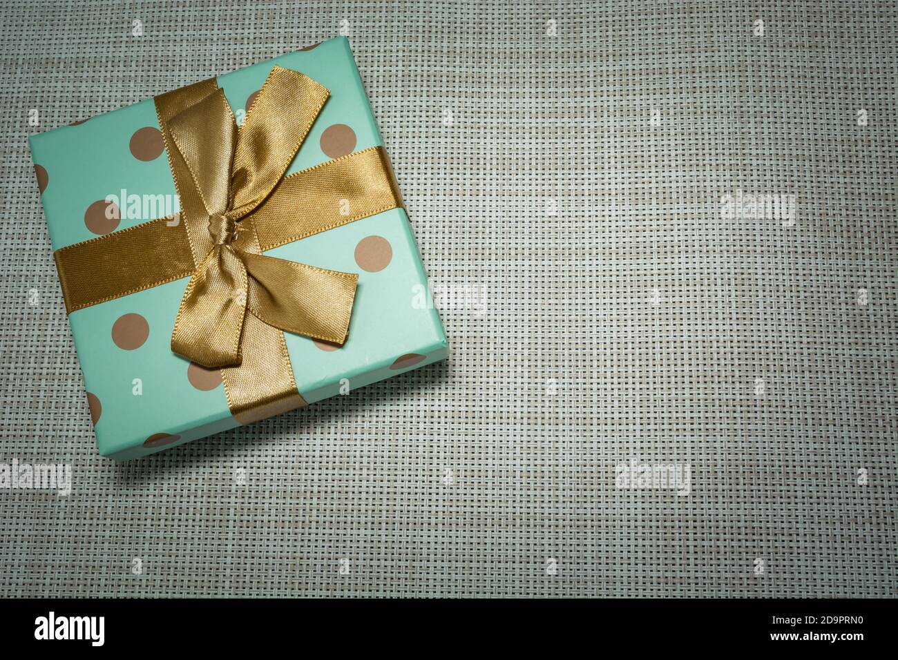 Regalo avvolto in carta celadon e nastro d'oro Foto Stock