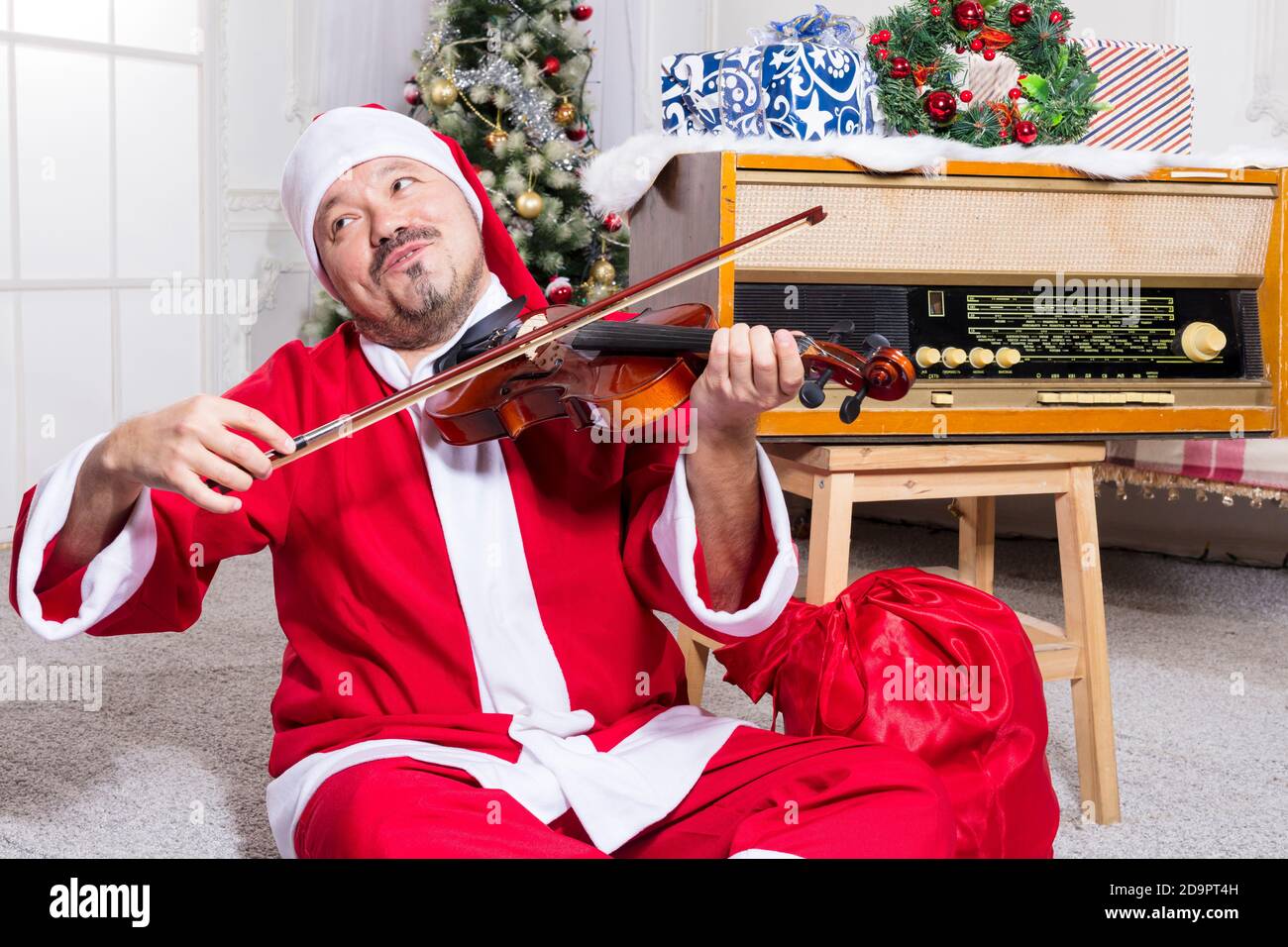 Uomo bearded vestito in costume di Babbo Natale che gioca studio di violine verticale Foto Stock