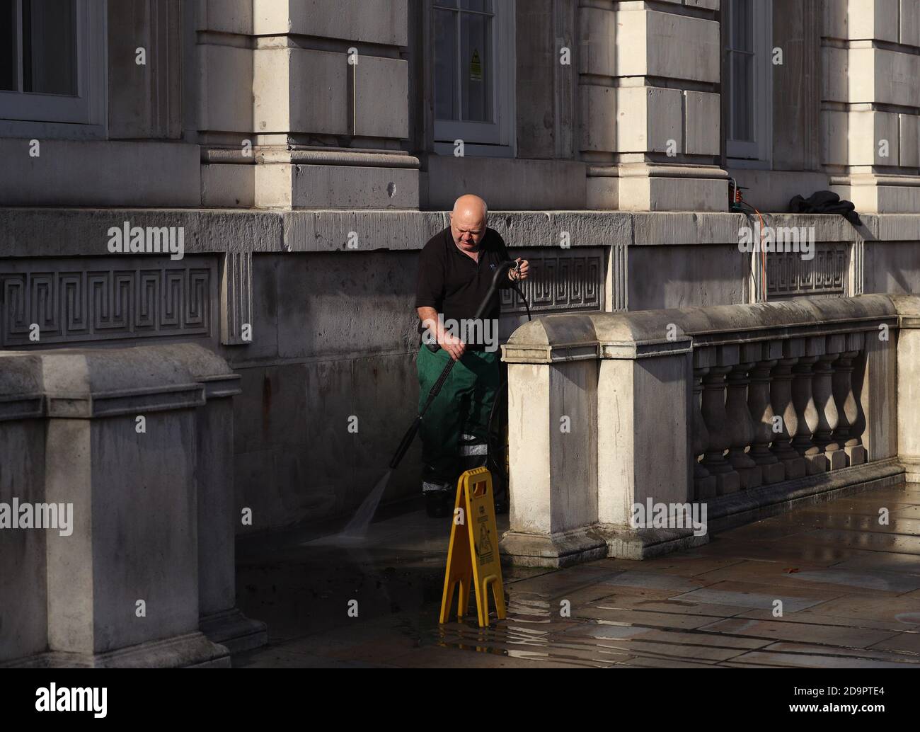 Un pulitore al di fuori dell'ufficio del gabinetto su Whitehall a Westminster, Londra, mentre i preparativi continuano prima della Domenica della memoria. Foto Stock