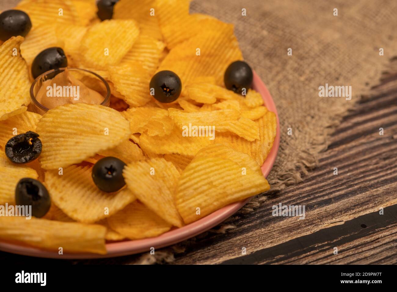 Patatine croccanti e deliziose con salsa di senape e olive su un panno di casa grossolano. Primo piano Foto Stock