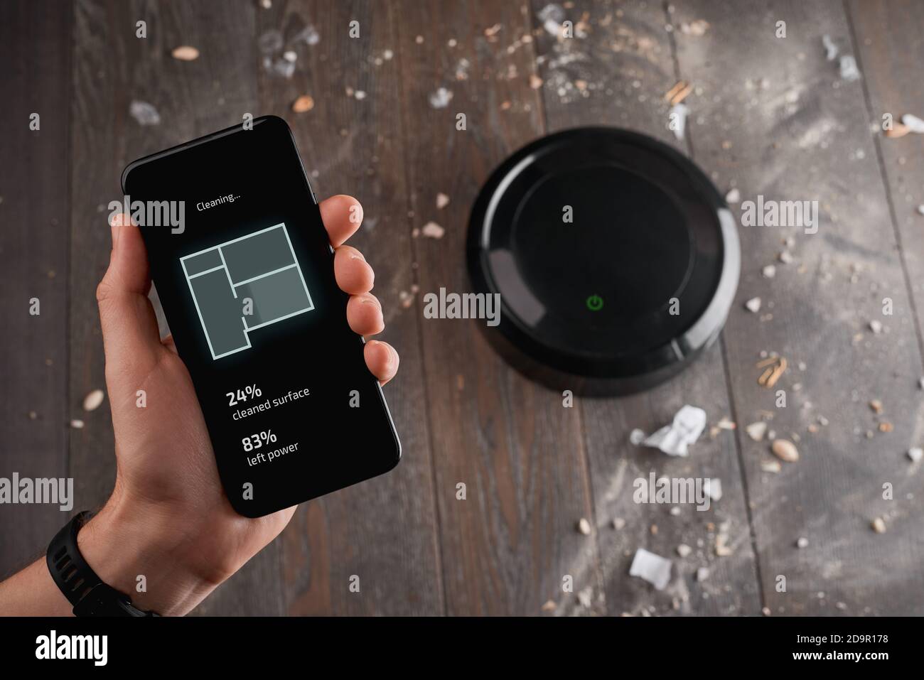 Uomo che utilizza un'app sul suo telefono abbinato a un pulitore robotizzato Foto Stock