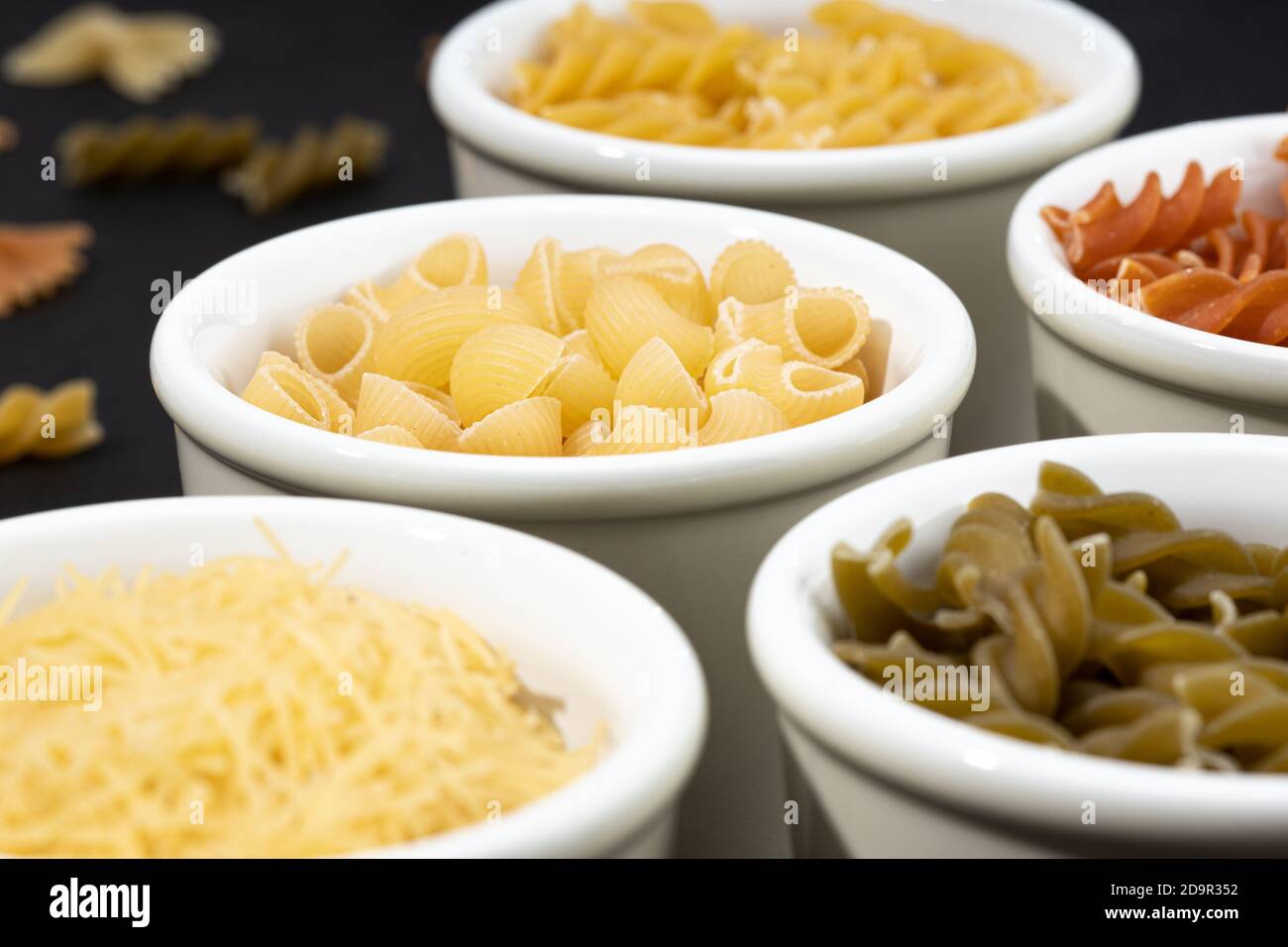 Gruppo di ciotole con pasta assortita non cotta. Cucina mediterranea Foto Stock