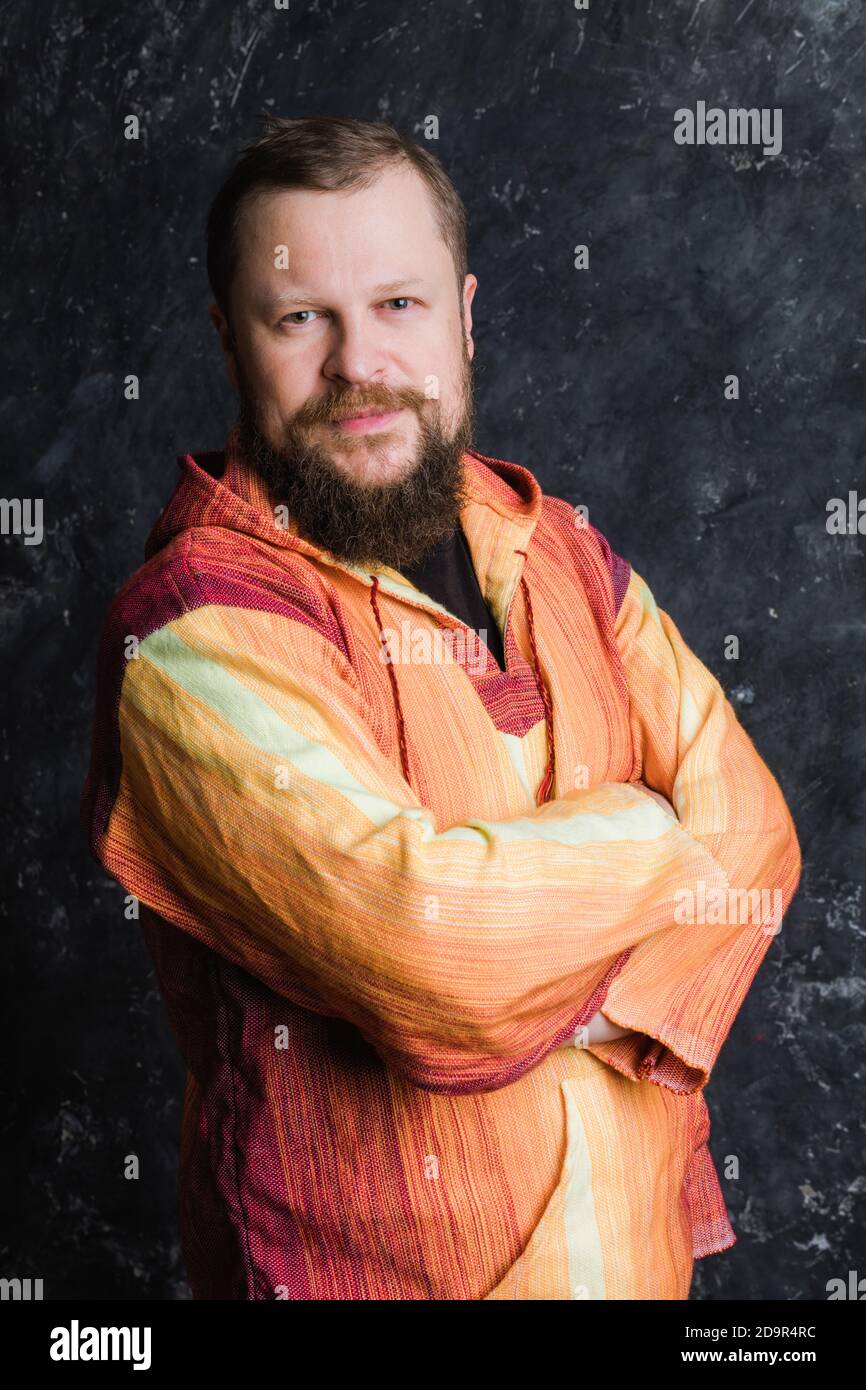 Uomo solido bearded in un ritratto in studio con mantello arancione brillante Foto Stock
