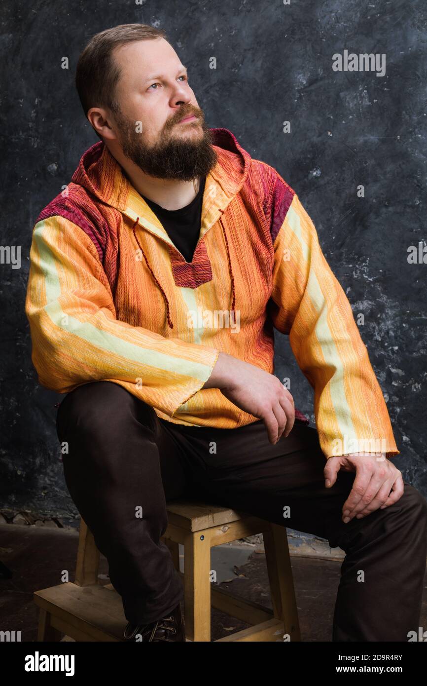 Uomo solido bearded in un ritratto in studio con mantello arancione brillante Foto Stock