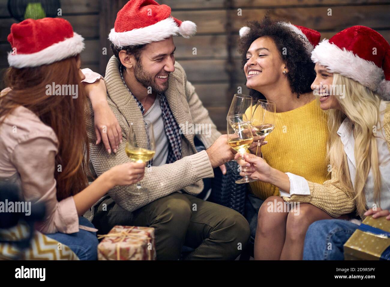 Gruppo di giovani felici che festeggiano insieme Natale o Capodanno; concetto di festa della casa Foto Stock
