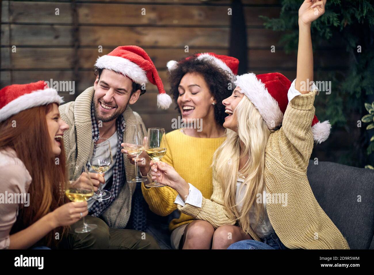 Gruppo di giovani felici che festeggiano insieme Natale o Capodanno; concetto di festa della casa Foto Stock