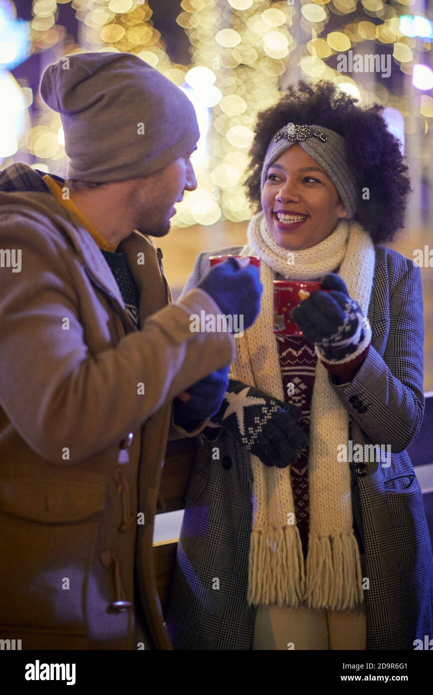 Felice coppia mista che ha un tè in un giorno d'inverno; concetto di sensazione di Natale Foto Stock