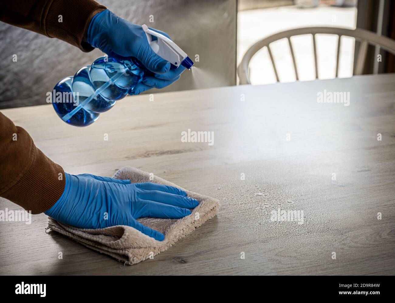 Pulizia delle superfici spruzzatura antibatterica liquido igienizzante con piano di lavaggio a casa . Uomo che usa guanti e asciugamani per la pulizia della molla. Foto Stock