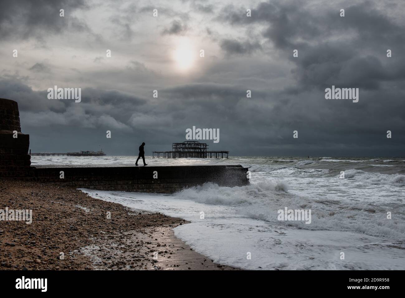 Un uomo che cammina sul groyne a Brighton durante un tempo tempestoso, Regno Unito Foto Stock